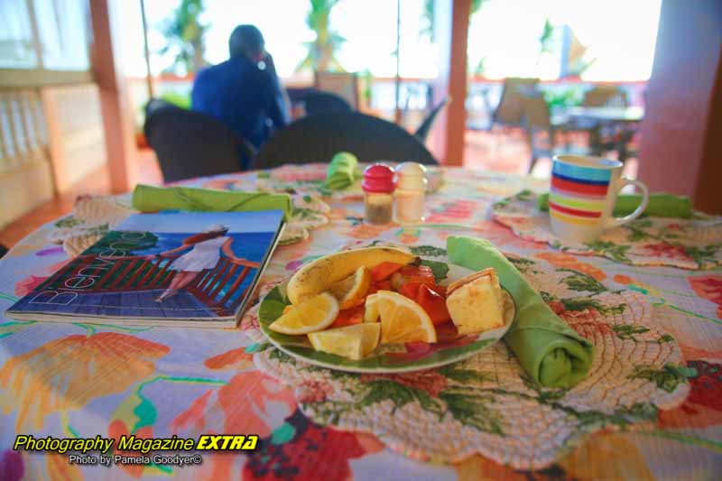 Breakfast on a colorful tablecloth with colorful fruit on the balcony.