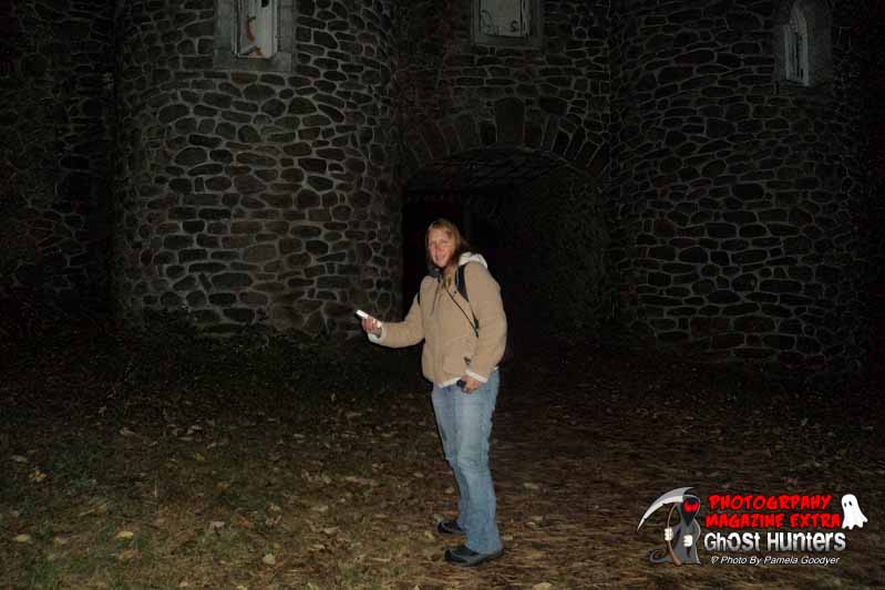 Erica Olson, standing in front of Dundas Castle ghost hunting with her ghost hunting meter in her hand.