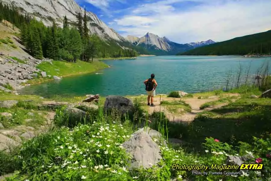 Jasper Canada Maligne Lake with a man staring out wearing a backpack.