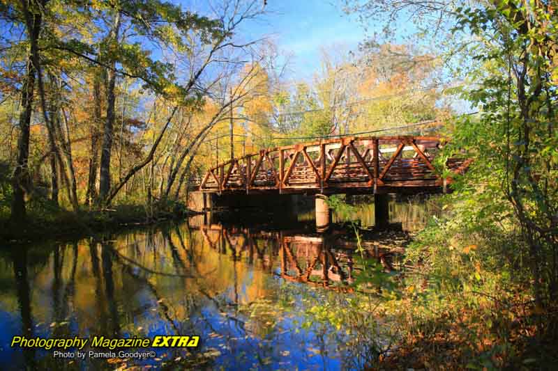 A bridge reflecting in the water in the fall foliage colors.